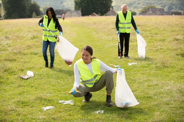 Personas que realizan servicio comunitario recogiendo basura al aire libre.