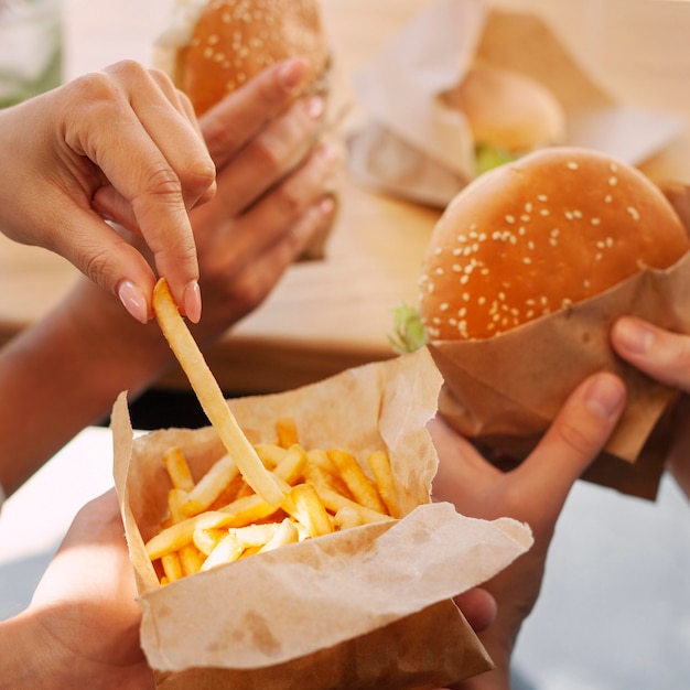 Personas que tienen comida rápida con papas fritas y hamburguesas