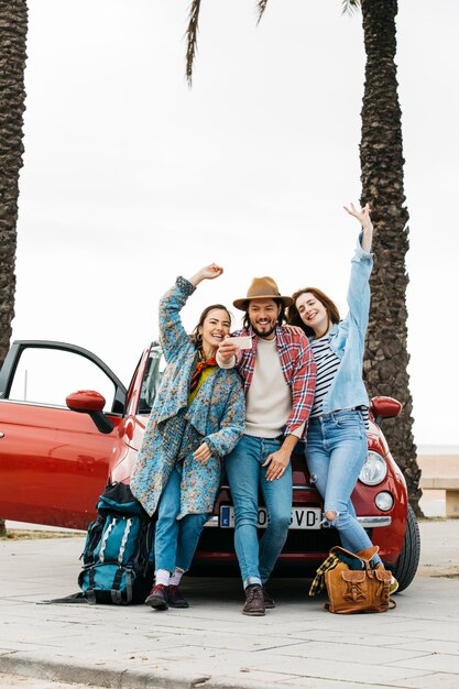 Personas que toman selfie cerca de coche rojo