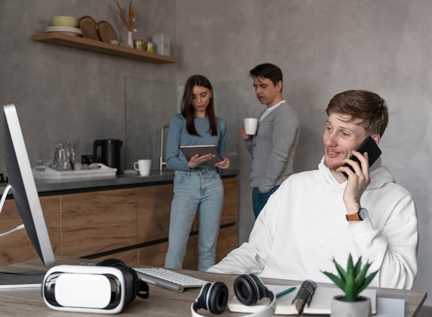 Personas que trabajan en el campo de los medios de comunicación con la computadora y hablando por teléfono.