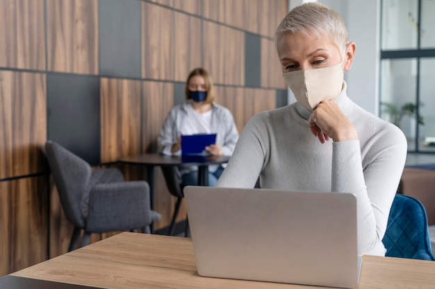 Foto gratuita personas que trabajan respetando la restricción de distanciamiento social