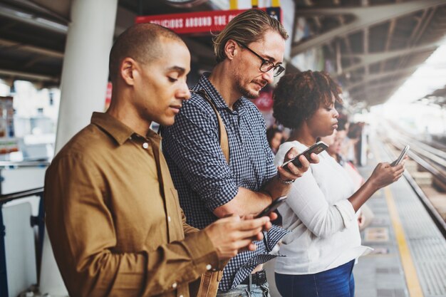 Personas que usan teléfonos inteligentes en la plataforma del tren