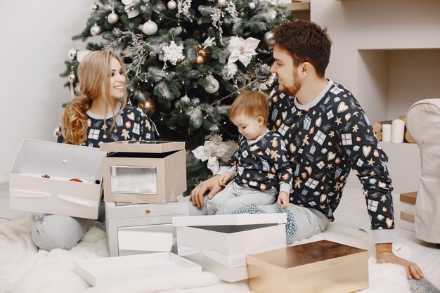 Personas reparando para Navidad. Gente jugando con niño. La familia está descansando en una sala festiva.