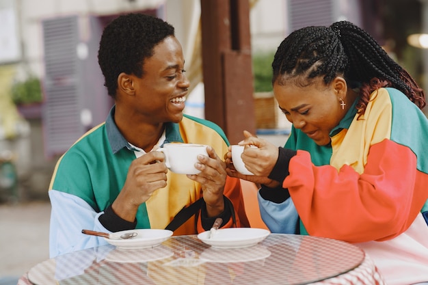 Personas con ropa de identificación. Pareja africana en la ciudad de otoño. Personas en la mesa.