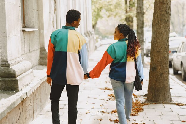 Personas con ropa de identificación. Pareja africana en la ciudad de otoño.