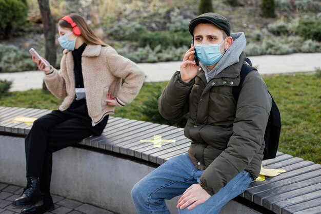 Personas sentadas a distancia y con máscara.