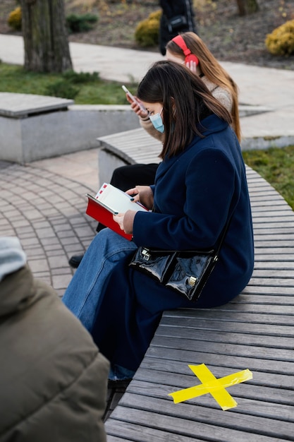 Personas sentadas a distancia y con máscara.