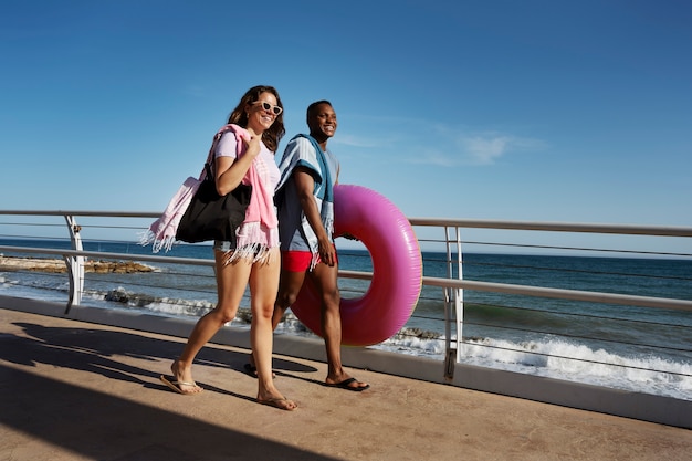 Foto gratuita personas sonrientes de tiro completo caminando en la playa