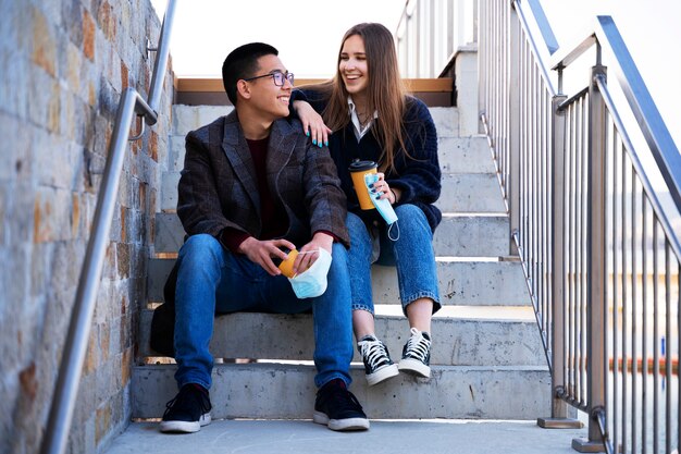 Personas sonrientes de tiro completo sentadas en las escaleras