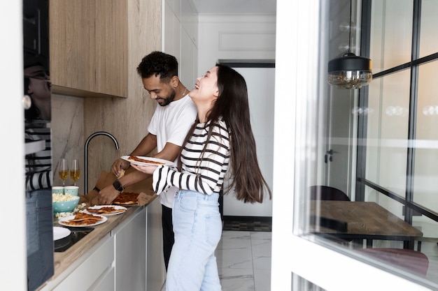 Personas sonrientes de tiro medio con comida en casa.