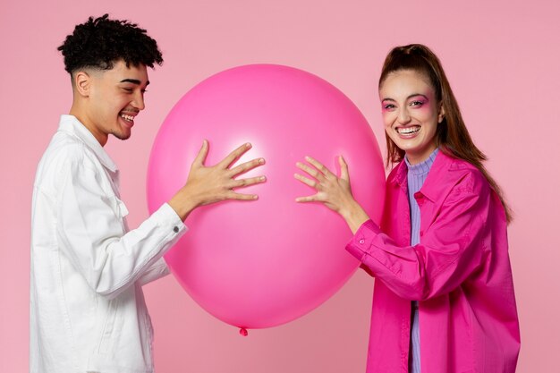 Personas sonrientes de tiro medio con globo rosa