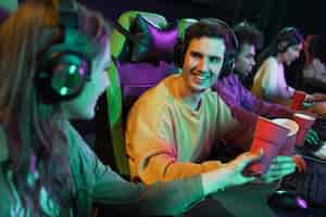 Foto gratuita personas sonrientes de tiro medio jugando videojuegos