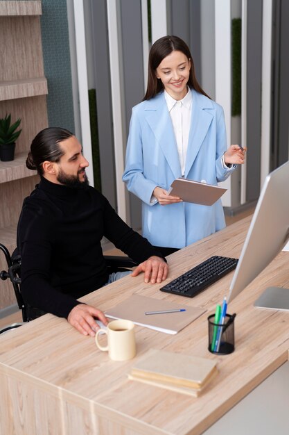 Personas sonrientes de tiro medio que trabajan con la computadora