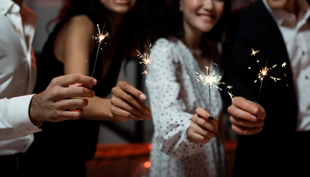 Personas sosteniendo bengalas en la fiesta de fin de año