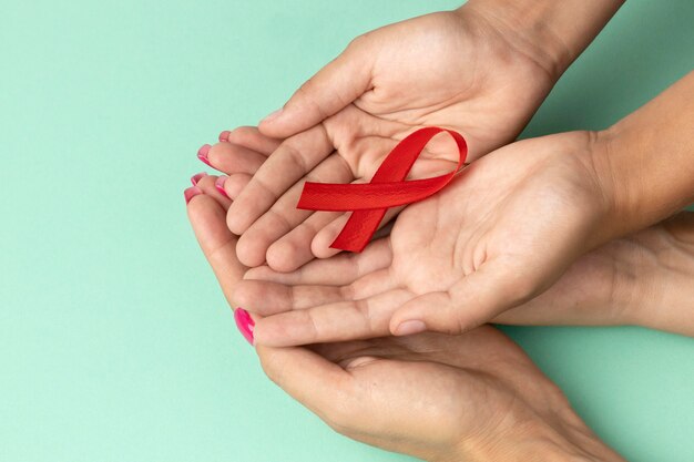 Personas sosteniendo un símbolo rojo del día mundial del sida