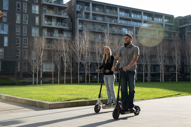 Personas de tiro completo que viajan con scooters eléctricos en la ciudad