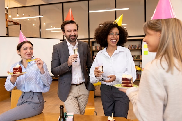 Foto gratuita personas de tiro medio celebrando cumpleaños en el trabajo.