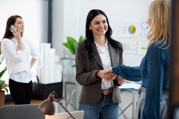 Personas de tiro medio dándose la mano en el trabajo