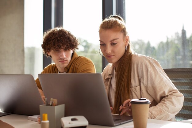 Personas de tiro medio que trabajan en computadoras portátiles