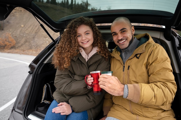 Personas de tiro medio sentadas en el baúl del auto