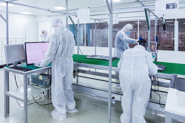 Personas en trajes aislantes blancos trabajando en laboratorio.