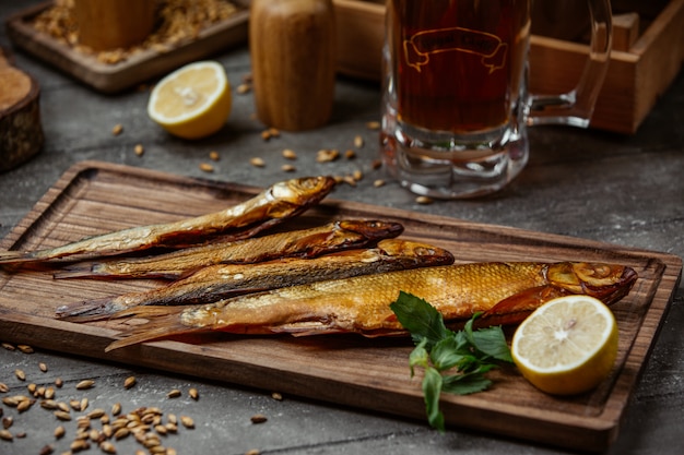 pescado ahumado seco servido con limón sobre tabla de madera para la noche de cerveza