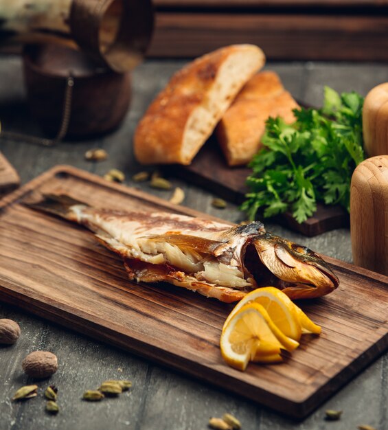 pescado ahumado en una tabla de madera con una rodaja de limón