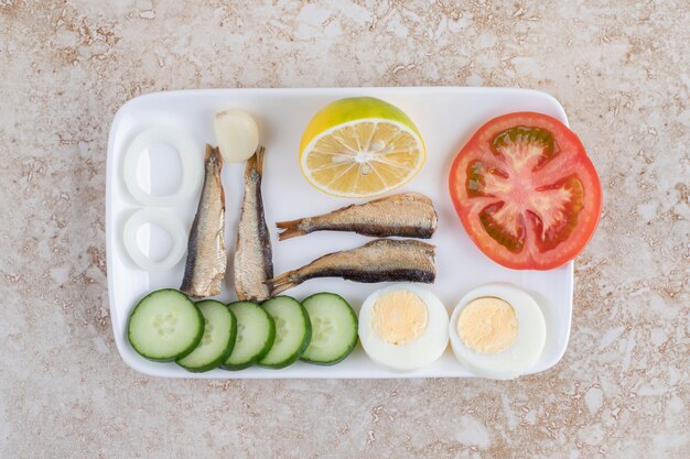 Pescado ahumado, verduras y huevos en un plato blanco