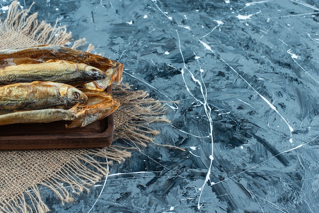 Pescado asado en una placa sobre la textura, sobre el fondo azul.