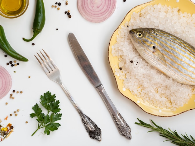 Pescado crudo alto ángulo con cubiertos