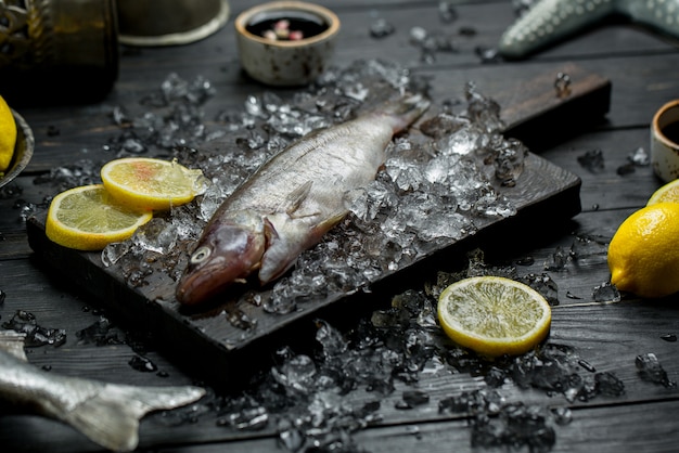 Pescado crudo fresco con rodajas de limón y cubitos de hielo picados.