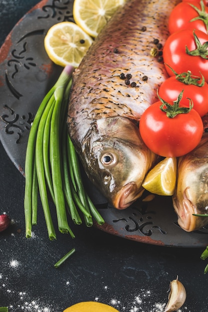 Pescado entero con hierbas, rodajas de tomate y limón.