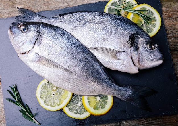 Pescado fresco con limón en tablero rústico