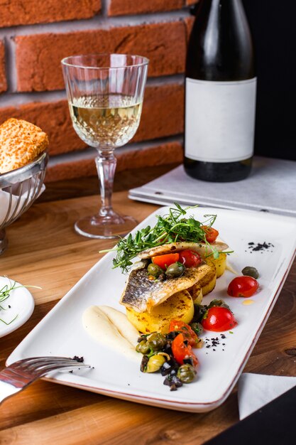 Pescado frito con papas, tomates, salsa y verduras.