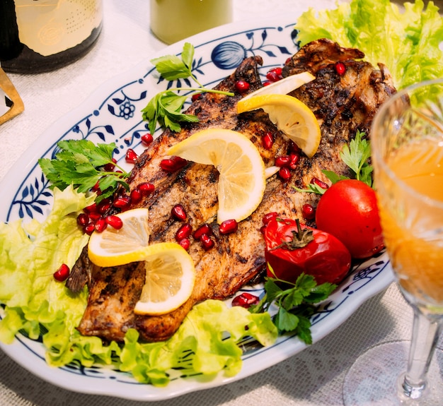 Foto gratuita pescado frito con rodajas de granada y limón