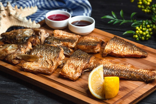 Pescado frito con salsas sobre tabla de madera