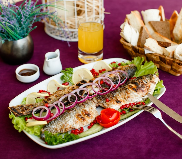 Pescado a la parrilla con cebolla roja, tomate, lechuga, limón y granada