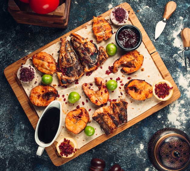 Foto gratuita pescado a la parrilla cortado en trozos servido en pan plano con salsas, zumaque