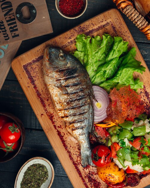 pescado a la parrilla con ensalada de verduras, cebolla y espolvoreado de zumaque