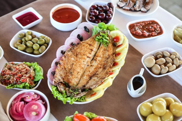 Pescado a la plancha en la tabla de madera encurtidos de limón salados cebolla lechuga