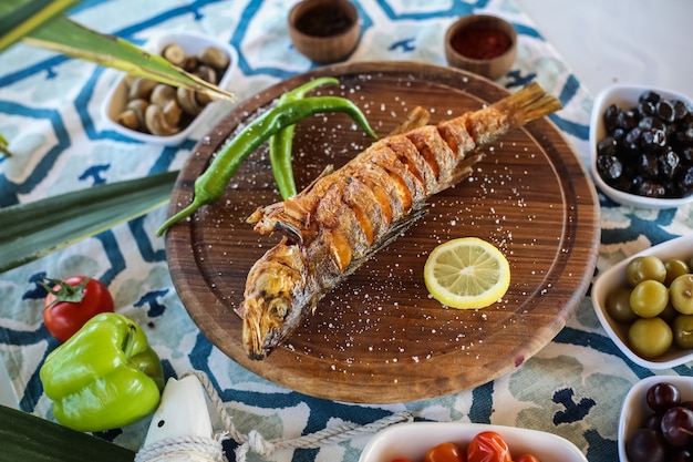 Foto gratuita pescado a la plancha en la tabla de madera encurtidos de limón salados