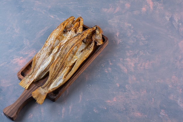 Pescado salado en una tabla, sobre la superficie de mármol