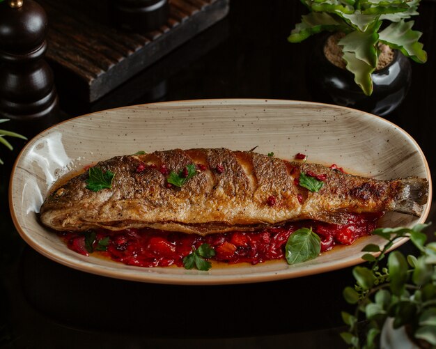 Pescado salteado en salsa de granada y servido en plato de granate