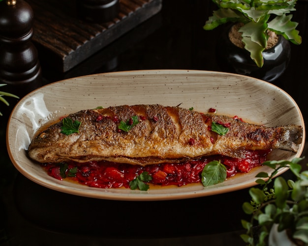 Pescado salteado en salsa de granada y servido en plato de granate