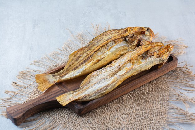 Pescado seco salado aislado sobre una tabla de madera