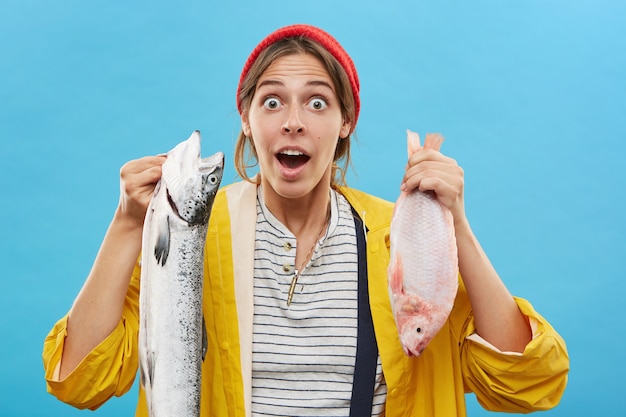 Pescador mujer sorprendida sosteniendo pescado