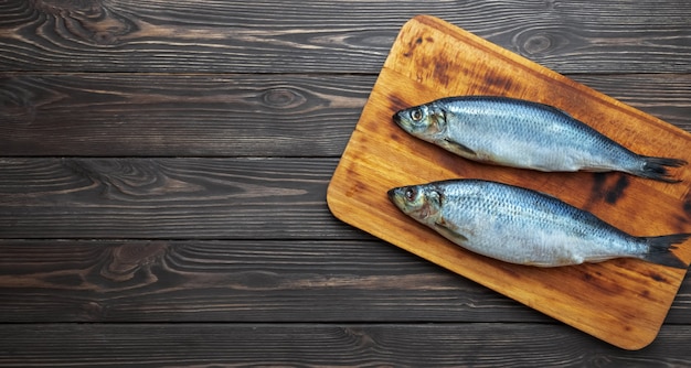 Pescados del arenque atlántico en escabeche sobre una tabla para cortar