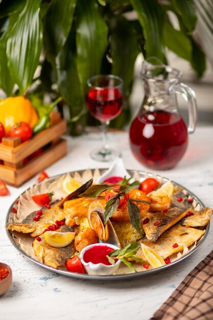 Pescados y mariscos asados a la parrilla, acompañados de hierbas, limón y salsa de tomate rojo.