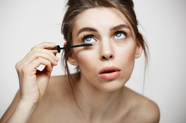 Pestañas hermosas jóvenes del tinte de la muchacha sobre el fondo blanco. Concepto de belleza salud y cosmetología. Tratamiento facial.