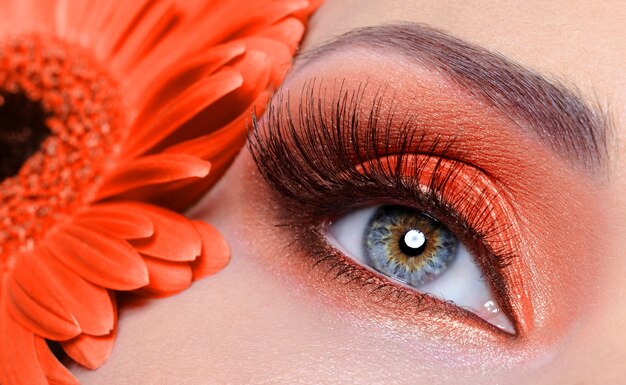 Pestañas postizas y maquillaje de ojos de moda con flor de naranja